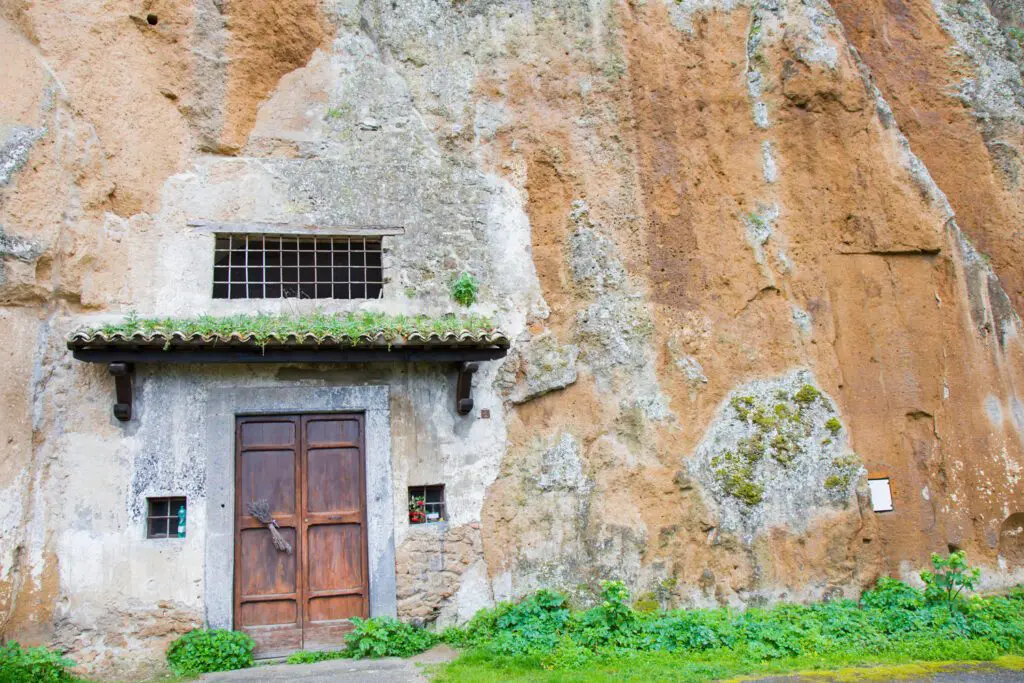 Ingresso della Chiesa del Crocifisso di Tufo. Una piccola porta di legno con una tettoia è ricavata nella rupe di tufo.