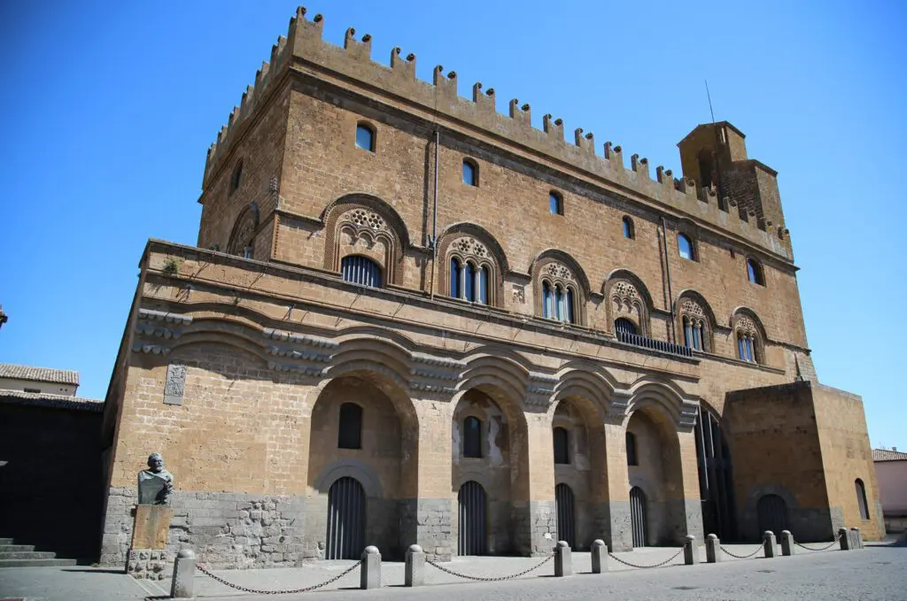 Vista scorciata dal basso del Palazzo del Popolo. In basso gli archi, sulla facciata le trifore e in alto i merli del palazzo.