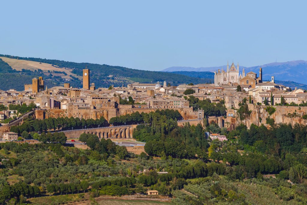 Vista della skyline di Orvieto dalla distanza, immersa nelle campagne umbre. Spiccano la facciata del duomo e la Torre del Moro.