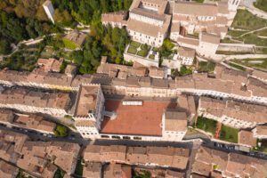 Vista aerea verticale di Piazza Grande. La grande piazza rossa è circondata dall'abitato e da Palazzo dei Consoli