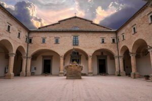 Vista di tre lati del quadriportico della Basilica di Sant’Ubaldo, con tre archi per lato, e un pozzo al centro del cortile.