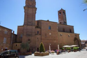 Esterno della Cattedrale di Città della Pieve. Il laterizio fa da padrone, come in tutto il borgo. Al centro della composizione il fianco della navata, che a sinistra termina con la torre campanaria, mentre a destra svetta la torre civica con orologio.