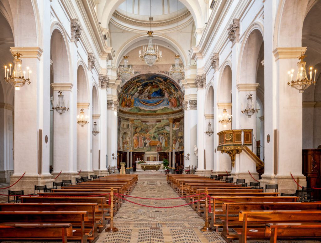 Vista della navata centrale della cattedrale di Spoleto. Il pavimento in serpentino, porfido e pietra conduce all'abside interamente affrescato.