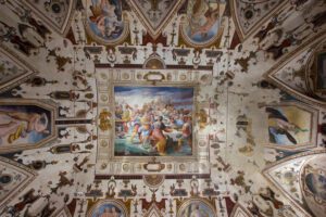 Vista a campo largo di un soffitto affrescato in una delle stanze di Palazzo della Corgna. Al centro la scena di un banchetto, mentre tutto intorno le grottesche vivacizzano e movimentano la decorazione.