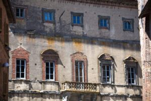 Vista della parte alta della facciata di Palazzo della Corgna. Diverse file di finestre scandiscono i livelli del palazzo, inserite in cornici dai richiami classici.