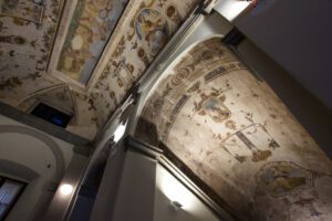 Vista di una sezione di una sezione della volta a botte che copre una scalinata e di una parte di soffitto. Entrambi sono ricoperti di grottesche, le decorazioni a tema animale e floreale che tappezzano i soffitti di Palazzo della Corgna.