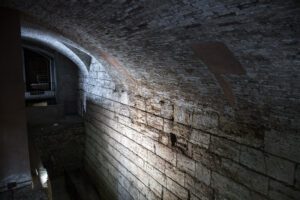 Vista dall'alto del muro di terrazzamento etrusco nella Perugia sotterranea. L'imponente muro, realizzato con grandi conci di travertino, è sormontato da una volta in mattoni.