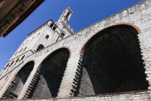 Vista dal basso di Piazza Grande. In primo piano i grandi archi che sorreggono la piazza pensile, sopra di essi palazzo dei consoli si slancia.