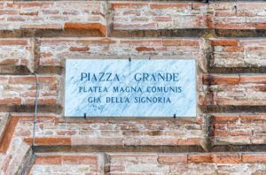 Targa che identifica Piazza Grande e recita “Piazza Grande, Platea magna comunis, Già della Signoria”