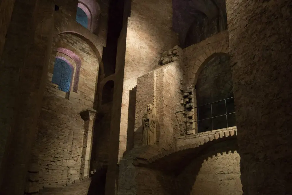 Dettaglio della muratura interna della Rocca Paolina. Vicino ad una serie di archi e finestre, a diversi metri di altezza dalla strada calpestatile, è posta una statua.