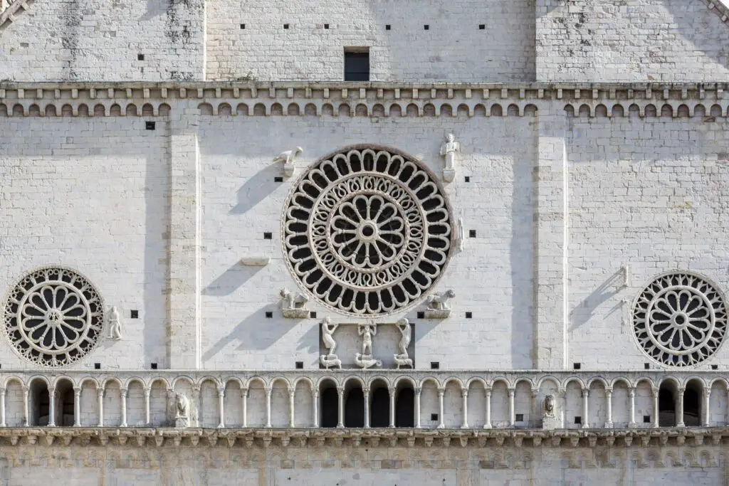 Dettaglio dei rosoni della facciata di San Rufino. Ai lati i due rosoni più piccoli e al centro il più grande sorretto dai telamoni.