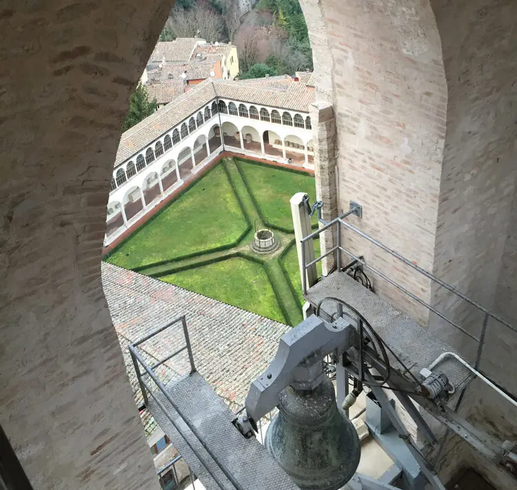 Vista del chiostro dal campanile di san domenico. In basso è visibile una campagna con il suo meccanismo di funzionamento, sopra di essa si apre, grazie all'arco ogivale, la vista sul chiostro sottostante con il suo prato ben curato.
