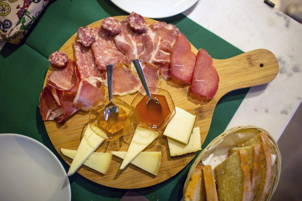 Vista dall'alto di un tagliere di prodotti tipici umbri: salumi, affettati, formaggi e marmellate e confetture in accompagnamento.